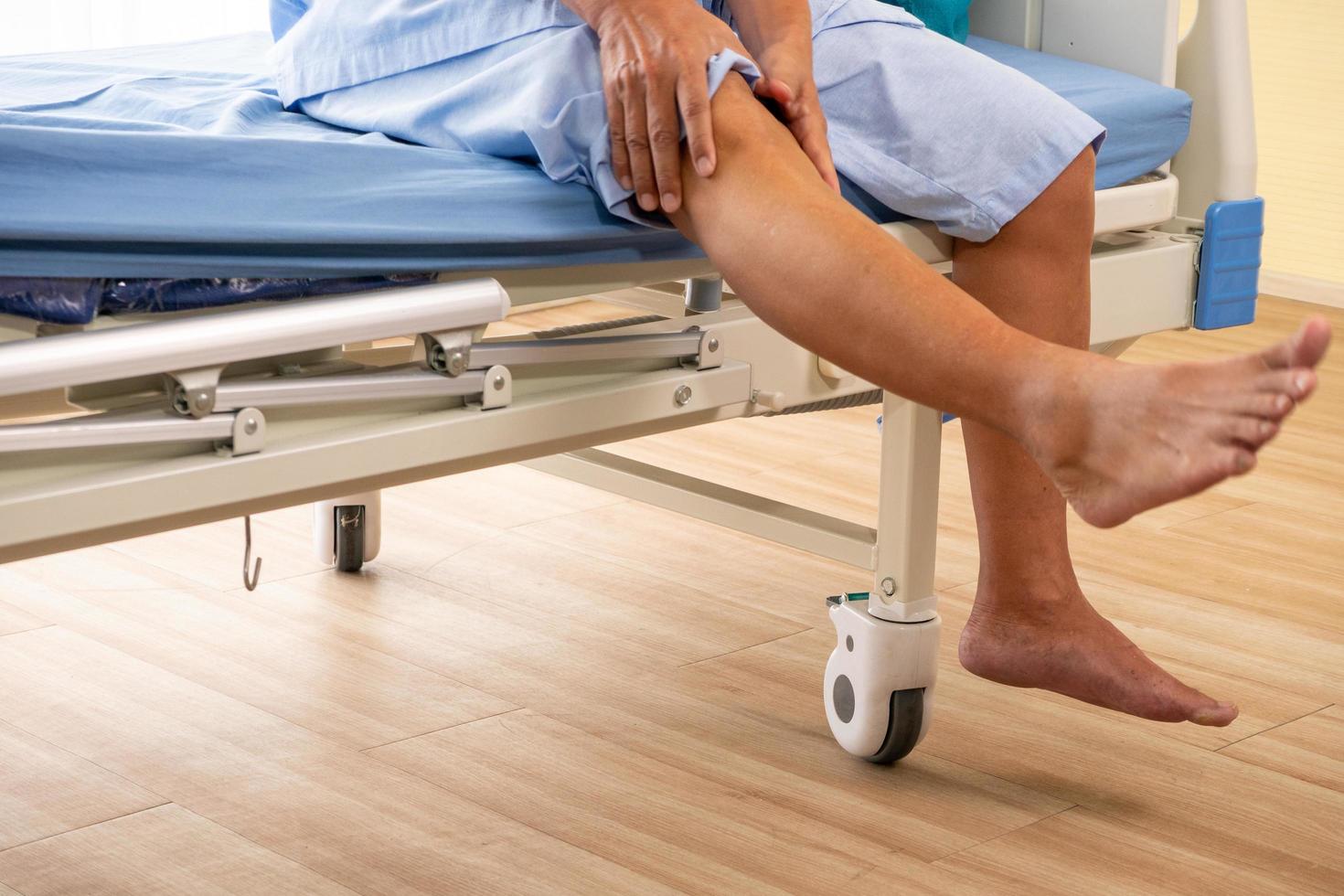 paciente asiático que siente dolor en la rodilla en la habitación del hospital. foto