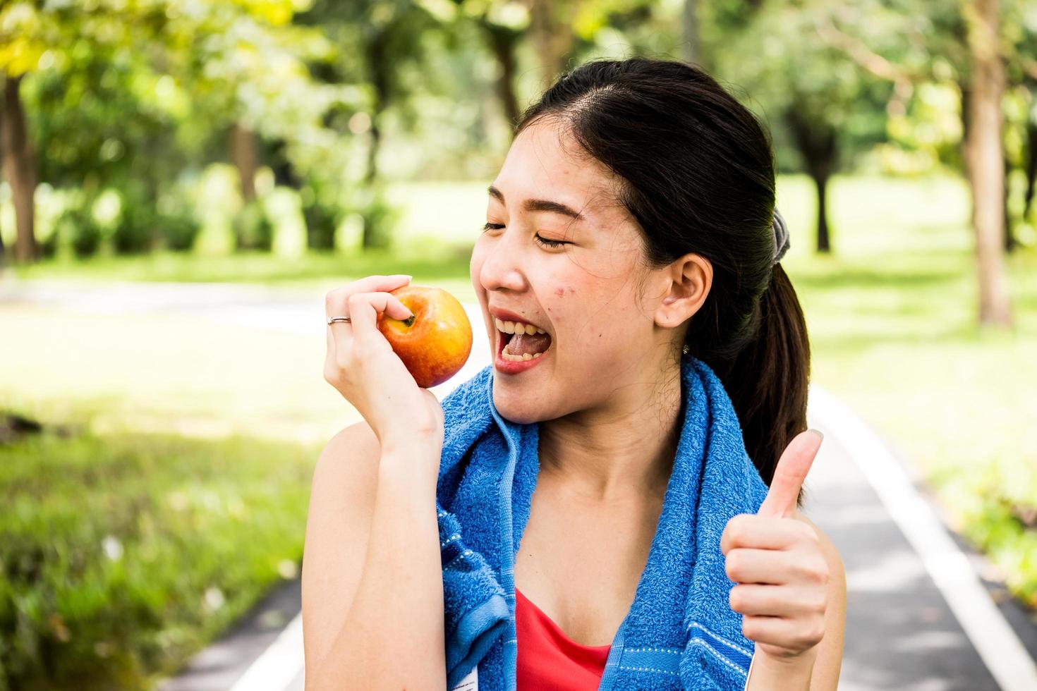Happy woman is holding apple in the park photo