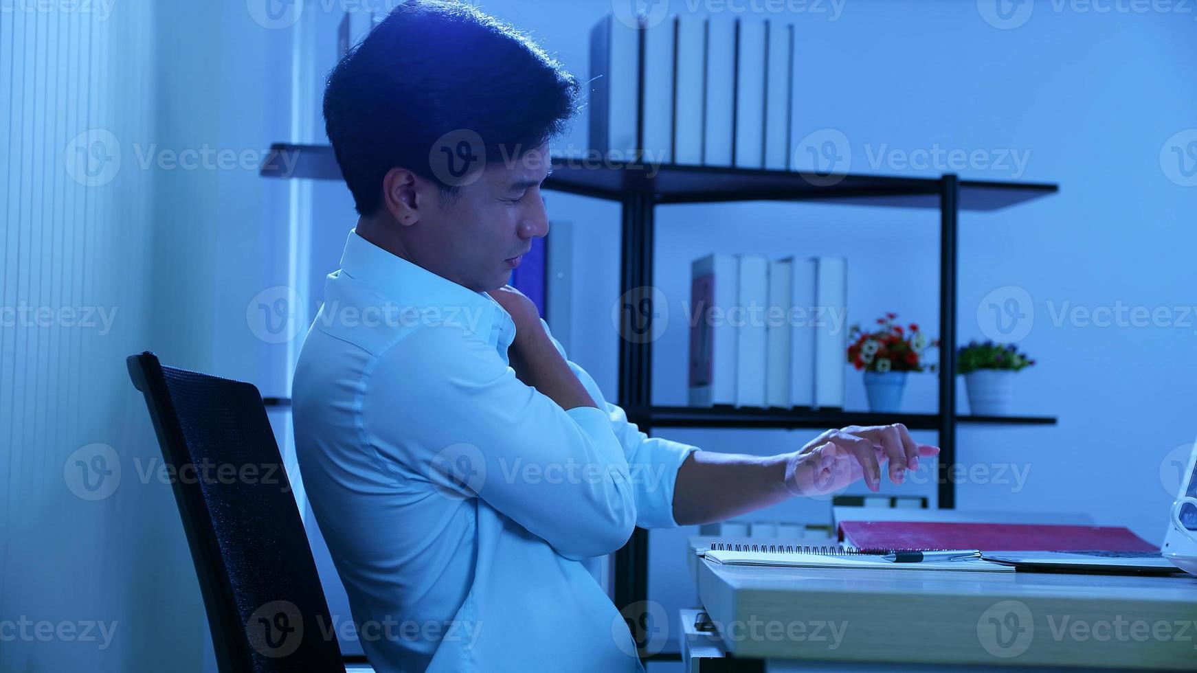 Office man sitting and working pain, He aches the body. And try to stretch the body, Over work at night in office photo
