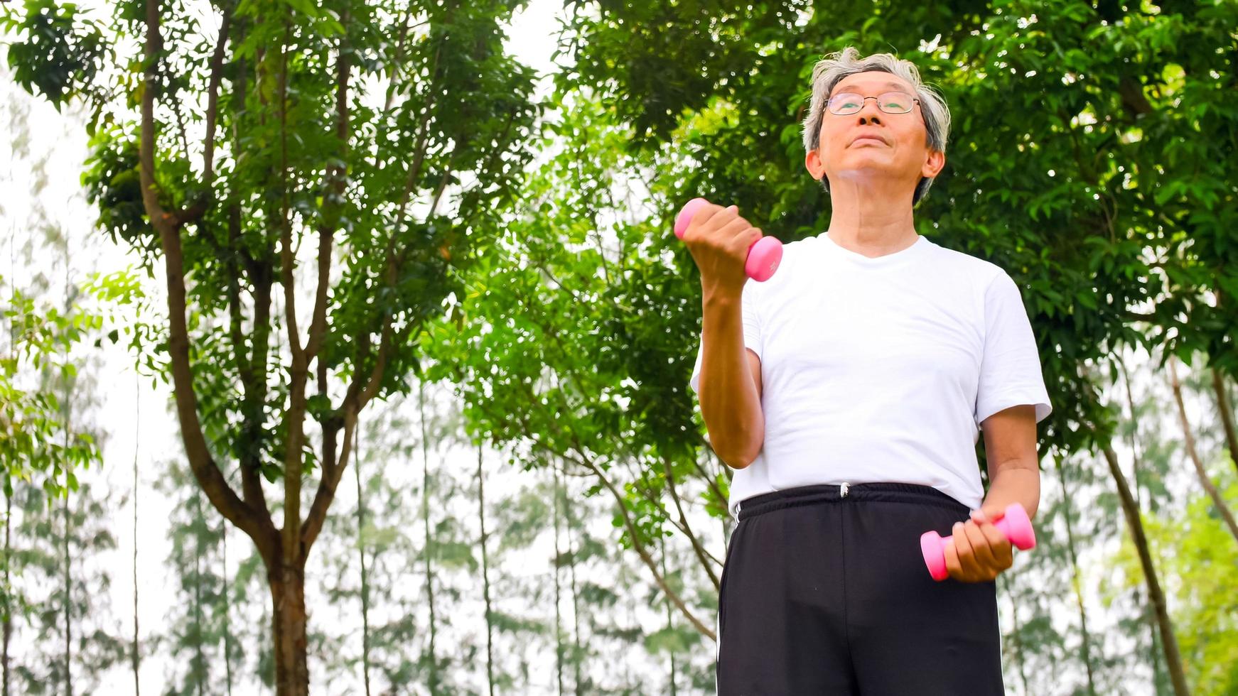 Asian man doing exercise by lifting dumbbells at the park. photo