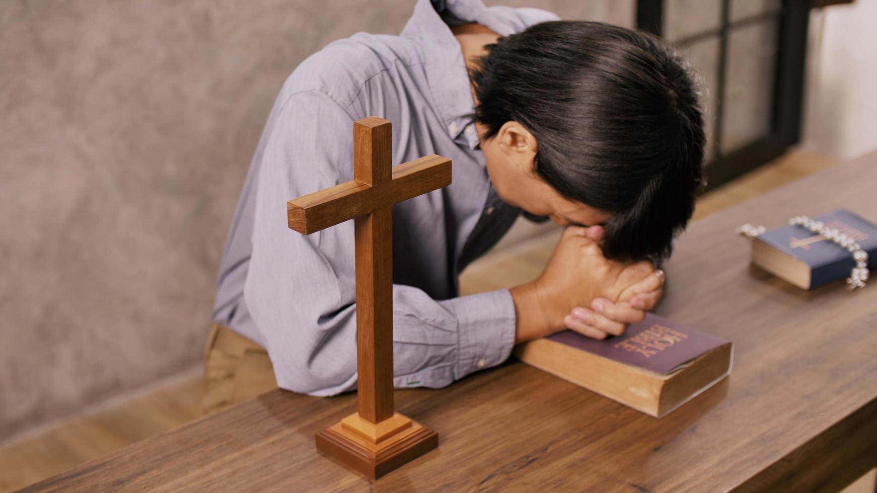 A young Asian Christian man praying to Jesus Christ in a church. photo