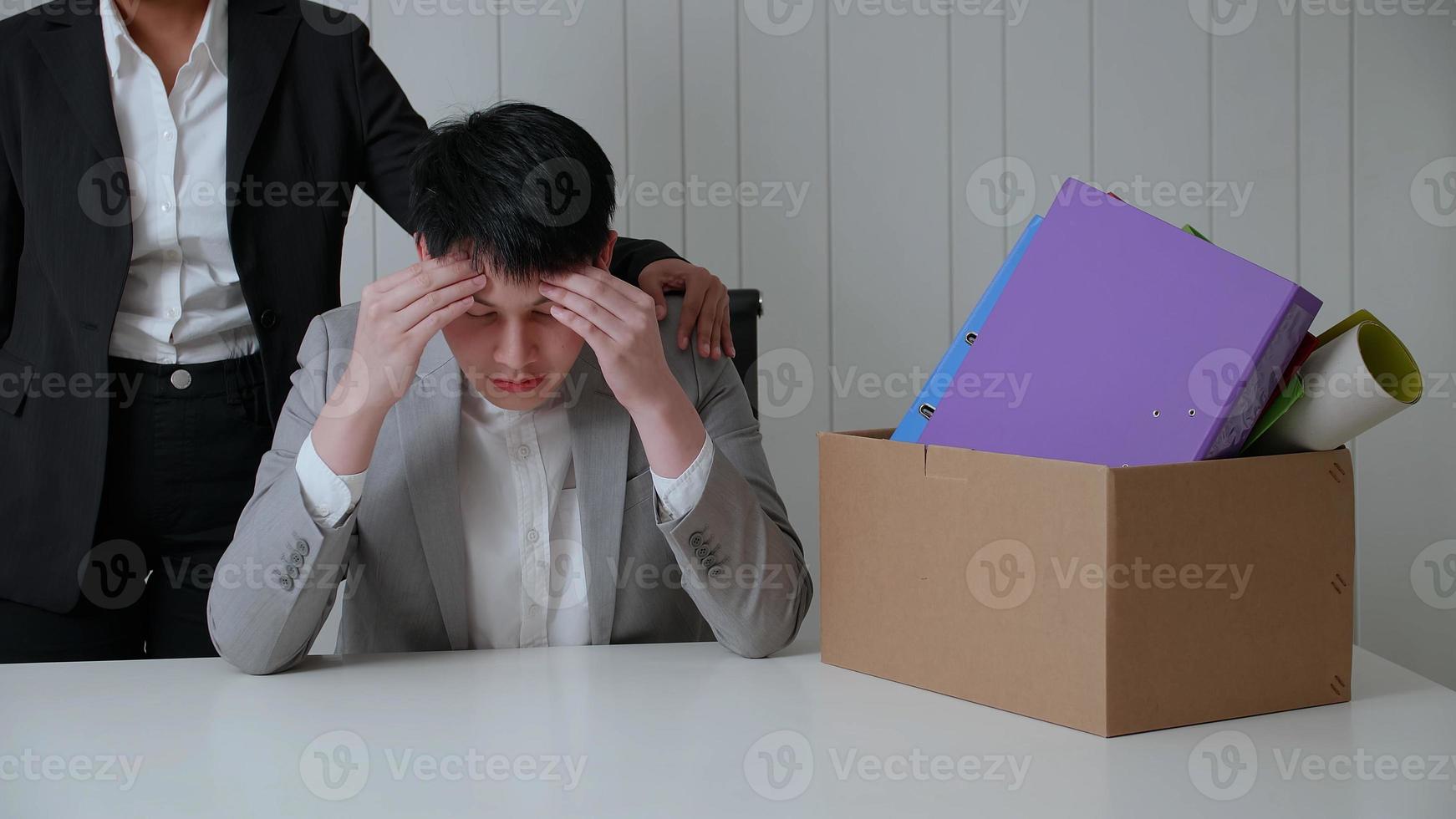 Young businessman is stressed because of being fired from his job. A colleague held his by the shoulder to encourage his. photo