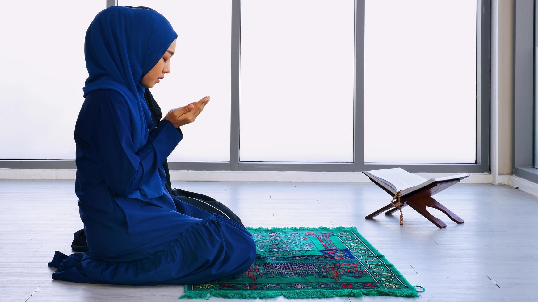 Muslim young woman in hijab is praying glorify Allah and practicing the Islamic faith in mosque. photo