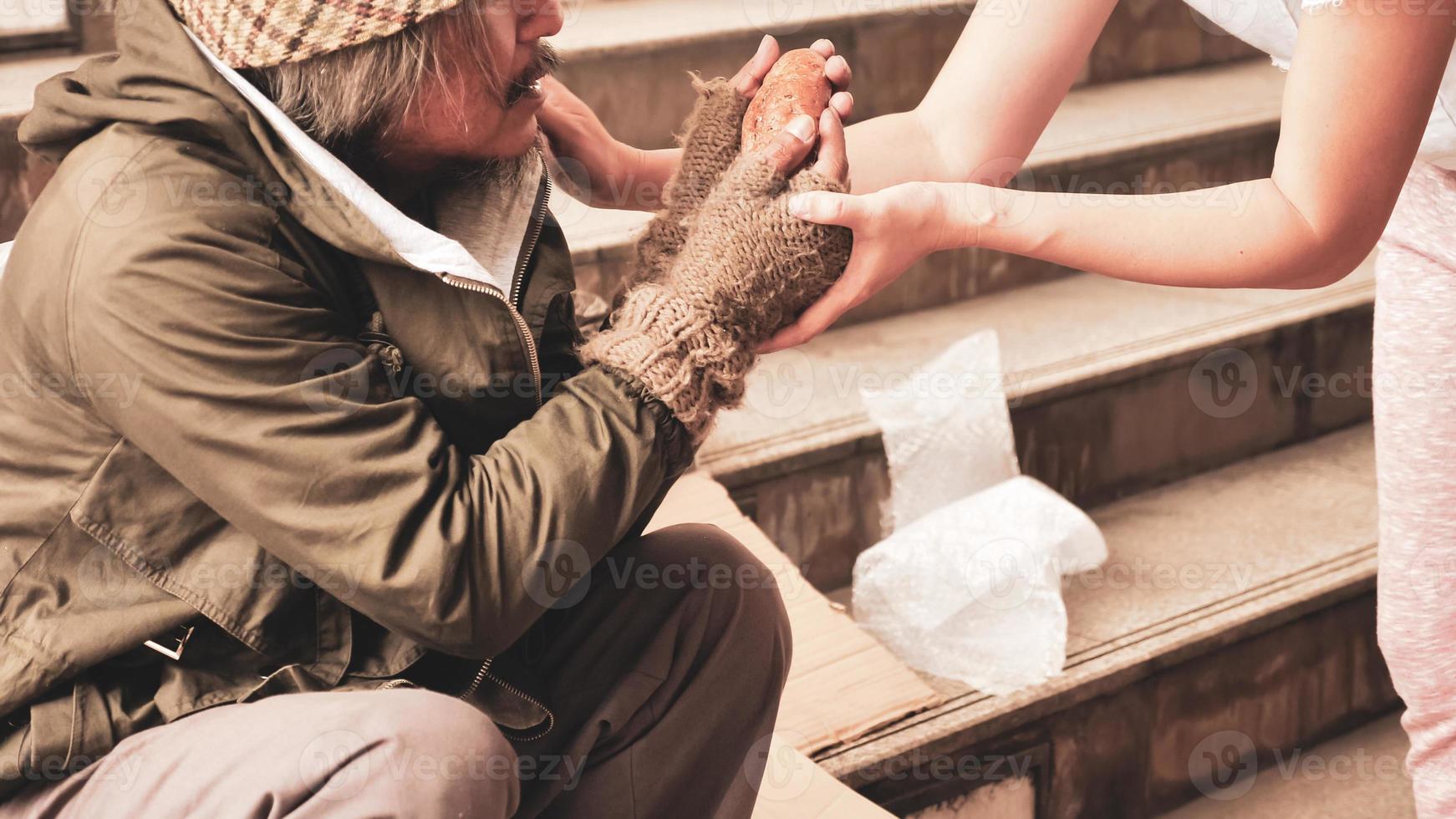 Woman giving food to homeless man who sitting on stairs. photo