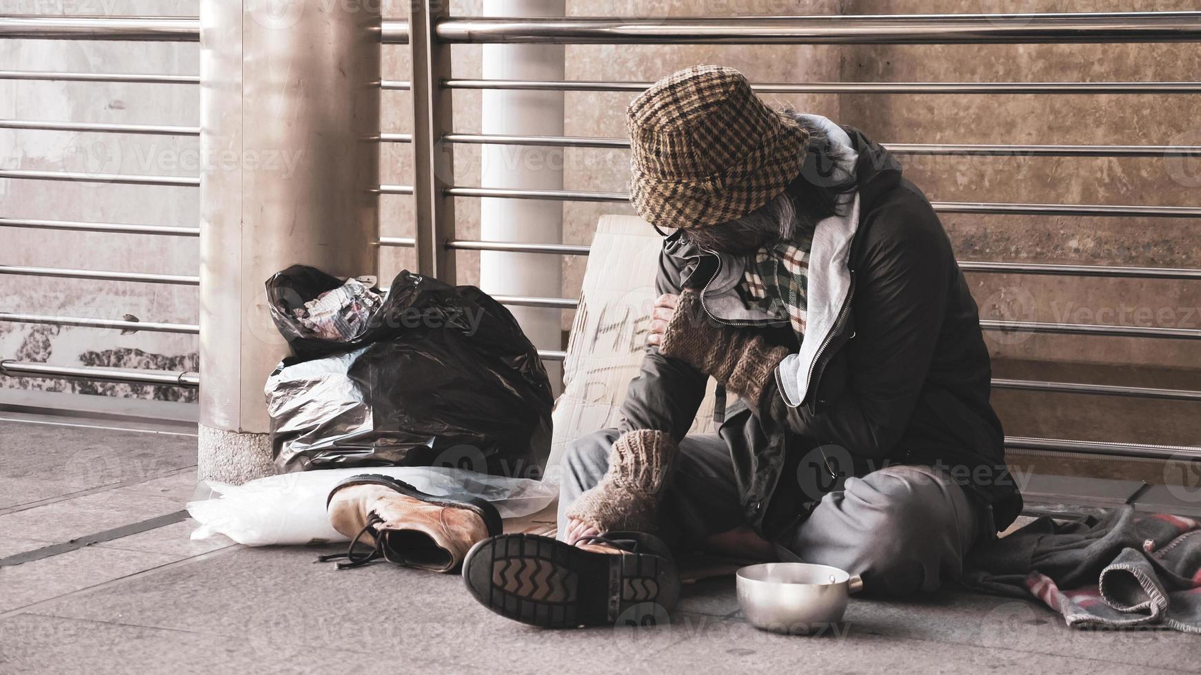 Homeless man sitting on outdoor floor. photo