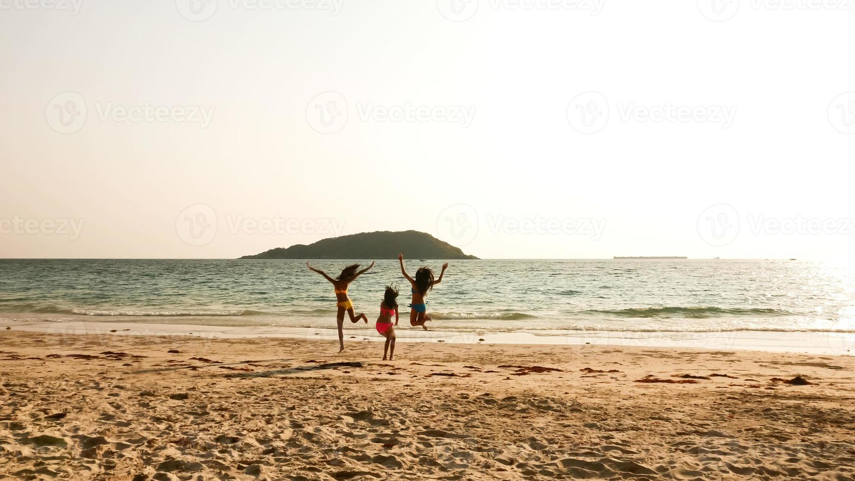 Three sexy women jumping together on the beach. photo