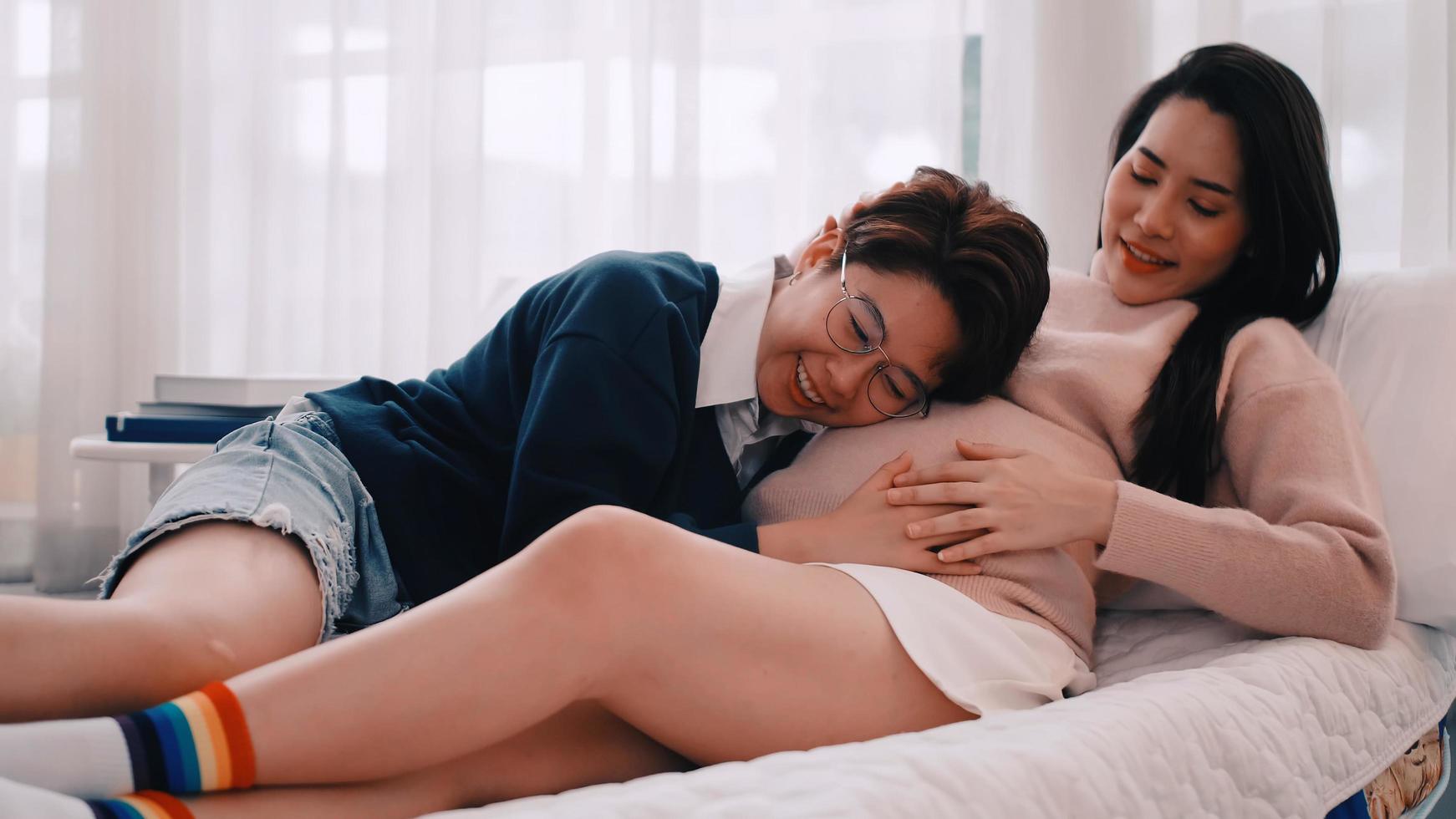 Pregnant Asian lesbian woman and her partner are happy to spend time together at home. photo