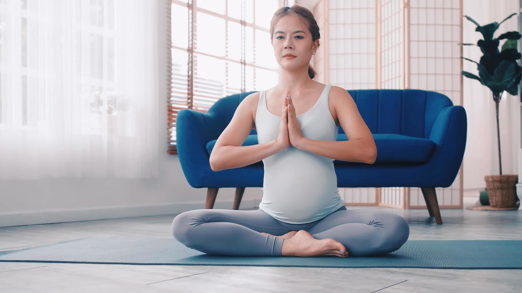 Asian pregnant woman doing yoga exercises at home. photo