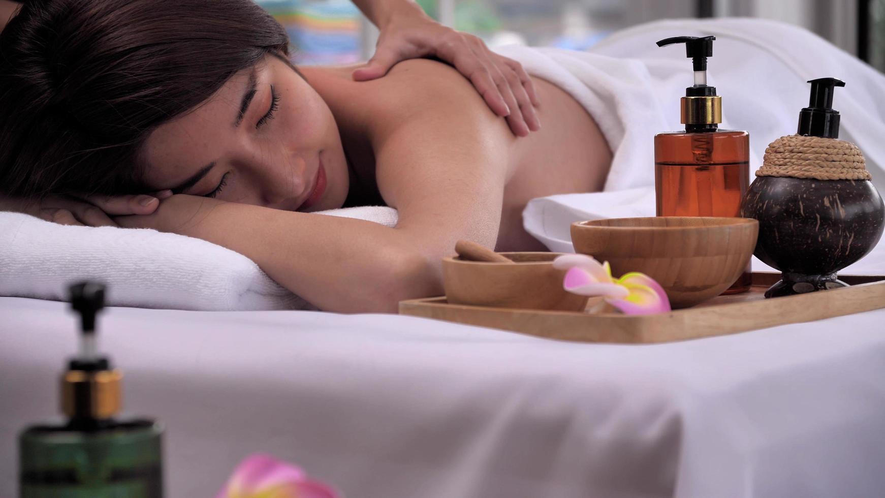 The massage therapist massaging on the back of young Asian woman with aroma essential oil skincare at spa salon. photo