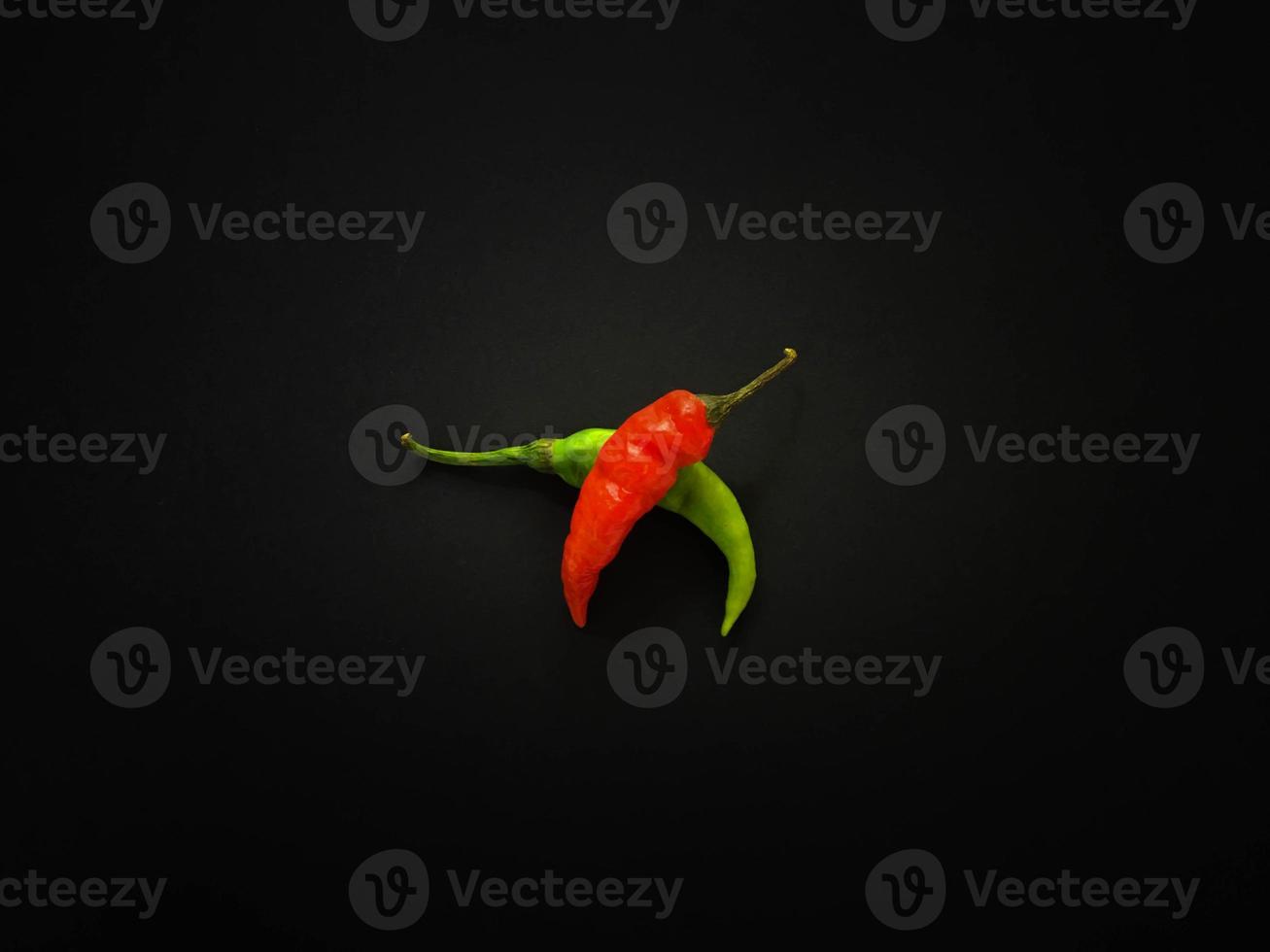 Natural green and red chilies on a dark background. Top view with food background, black stone table, copy space. photo