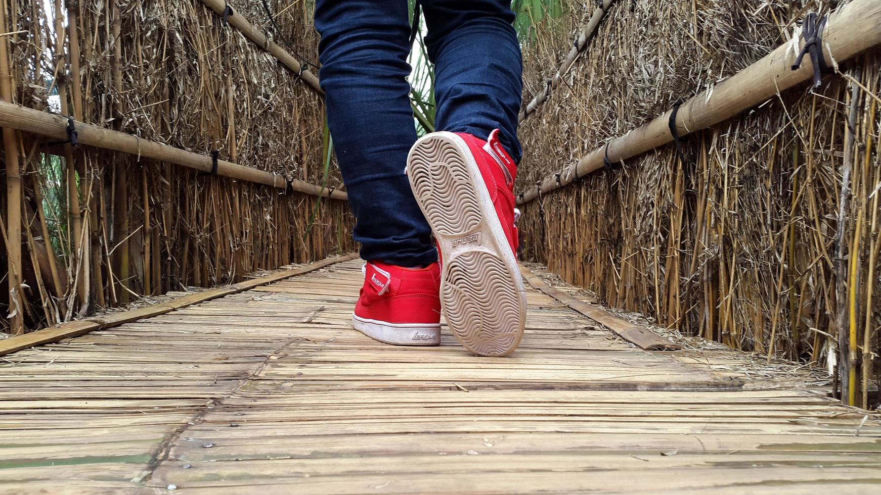 man's feet are walking on the bridge in red shoes and white soles photo