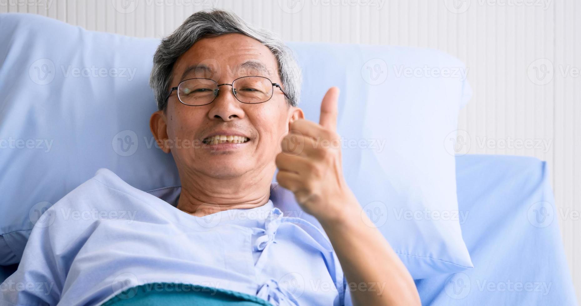 Male patient smiling and lying down on sickbed in hospital room. photo