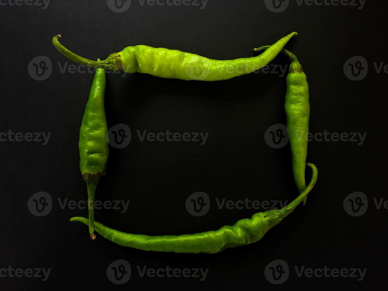 Natural green chilies on a dark background. Top view with food background, black stone table, copy space. photo