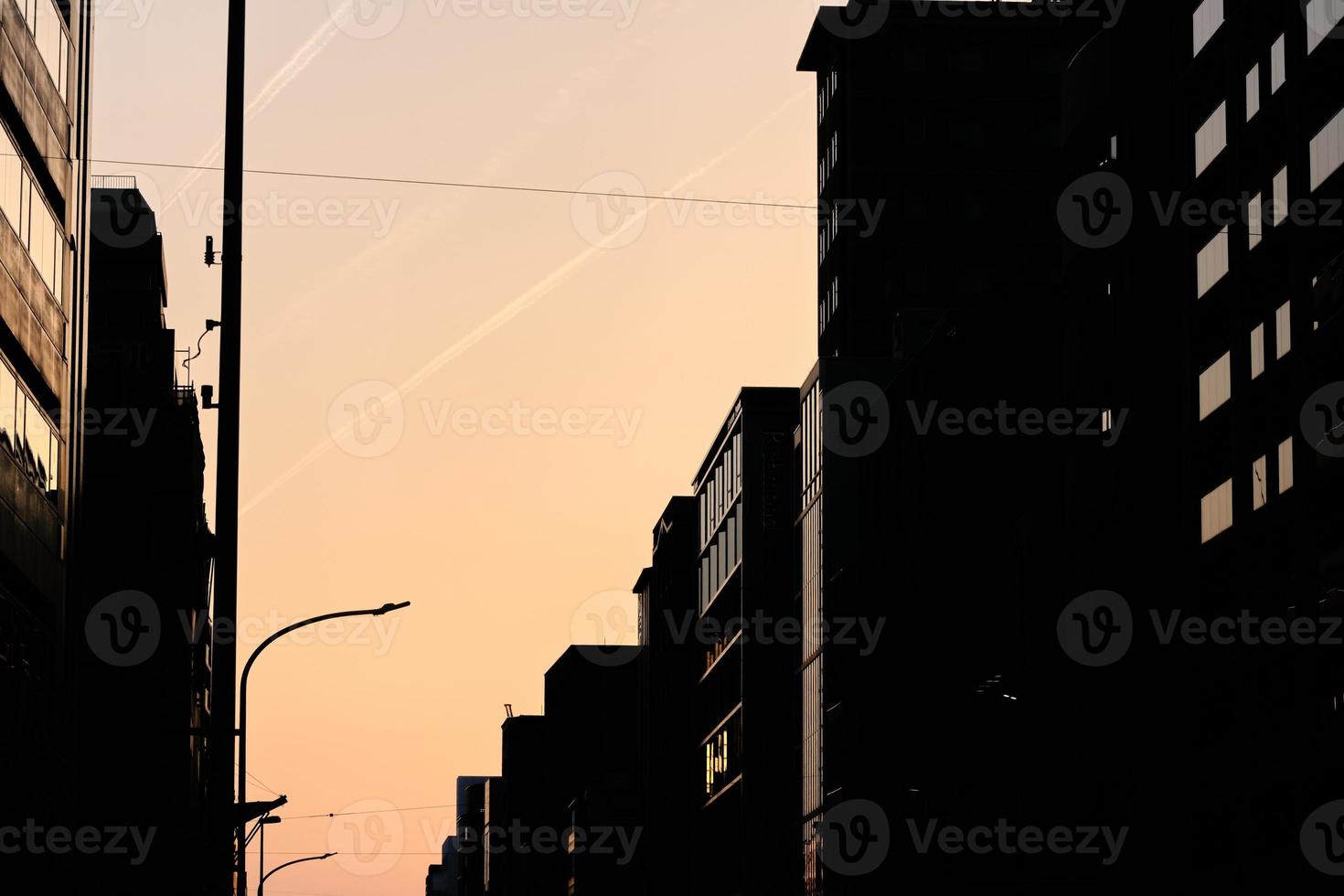 Contrails over downtown buildings in silhouette at dusk photo