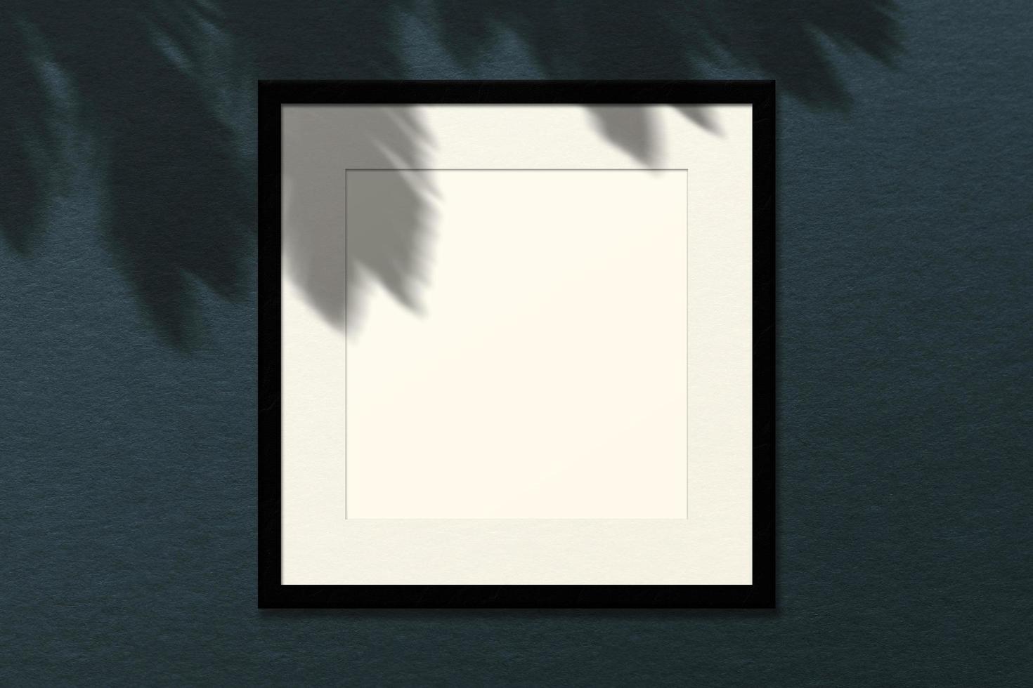 Minimal empty square white frame picture mock up hanging on wall background with leaves window. photo