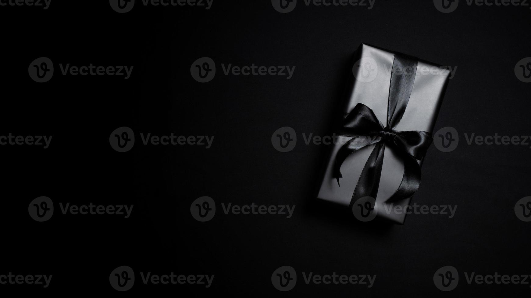 Top view of black gift box with black ribbons isolated on black background. photo