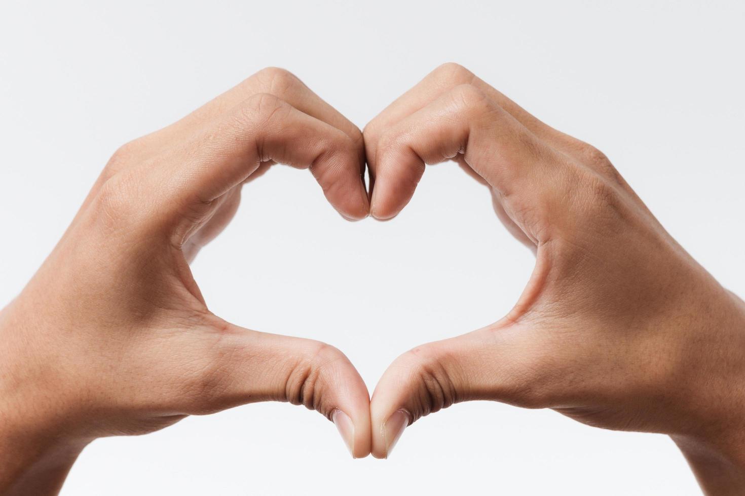 manos del hombre haciendo una forma de corazón sobre un fondo blanco aislado foto