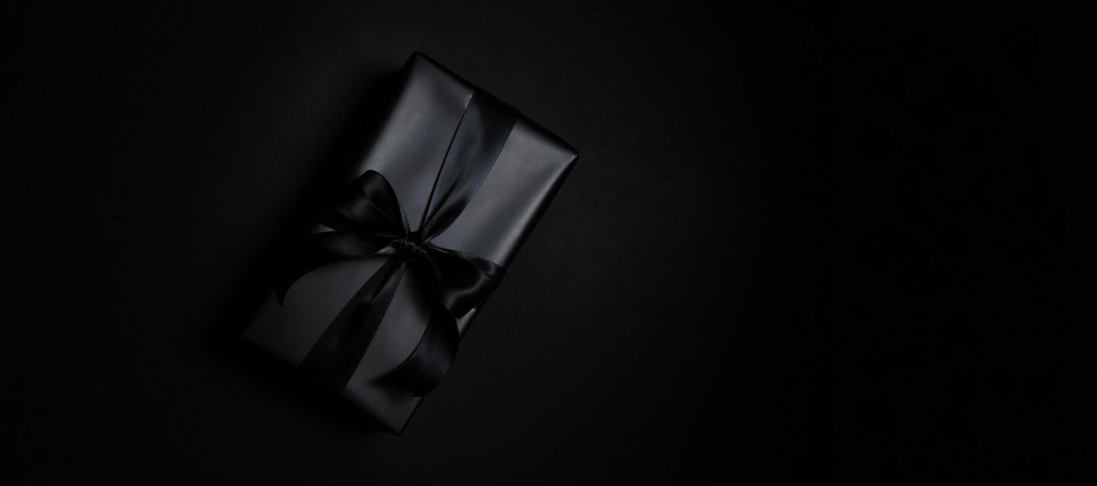 Top view of black gift box with black ribbons isolated on black background. photo