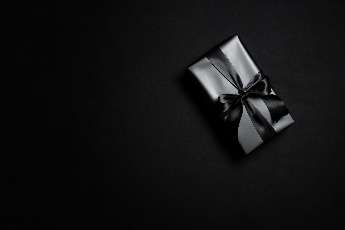 vista superior de la caja de regalo negra con cintas negras aisladas sobre fondo negro. foto
