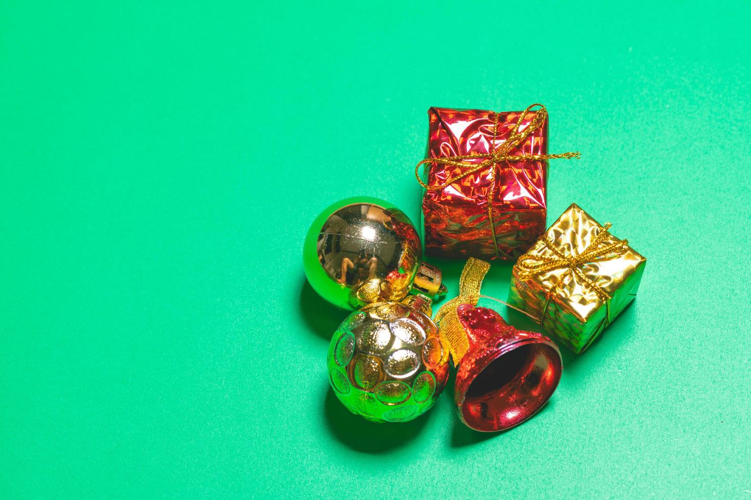 Top view of Christmas gift box red balls with spruce branches and bell on green background. photo