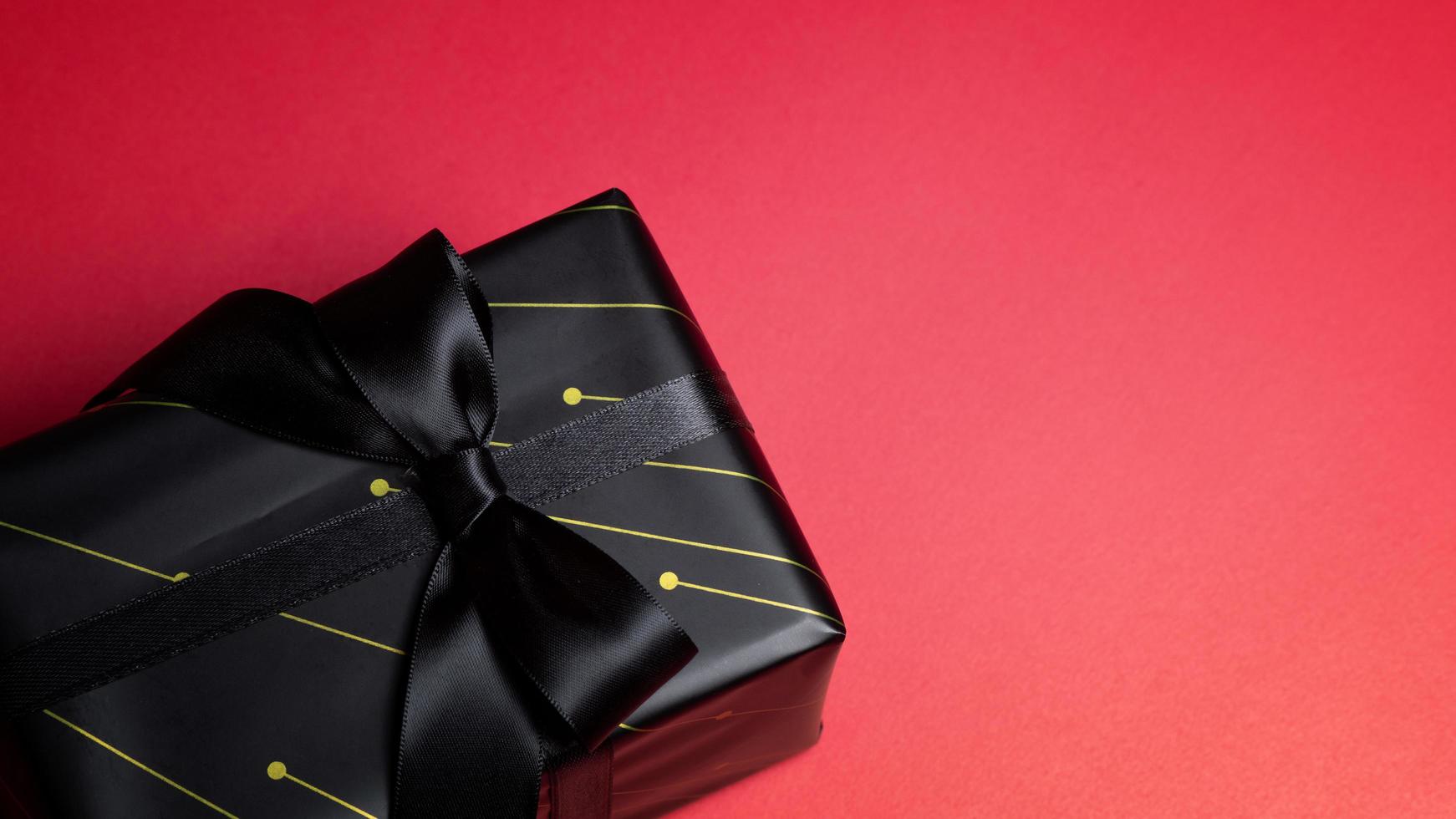 Top view of black gift box with red and black ribbons isolated on red background. photo