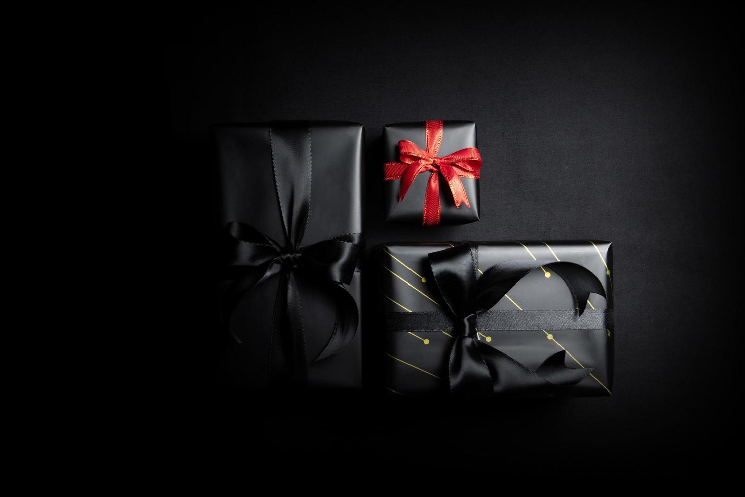 Top view of black gift box with black ribbons isolated on black background. photo