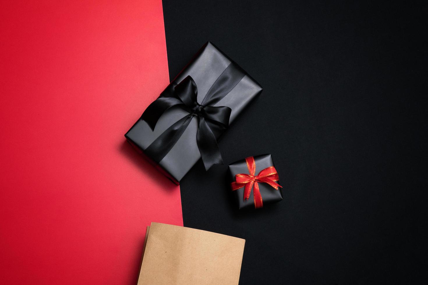 Top view of black gift box with red and black ribbons isolated on black background. photo