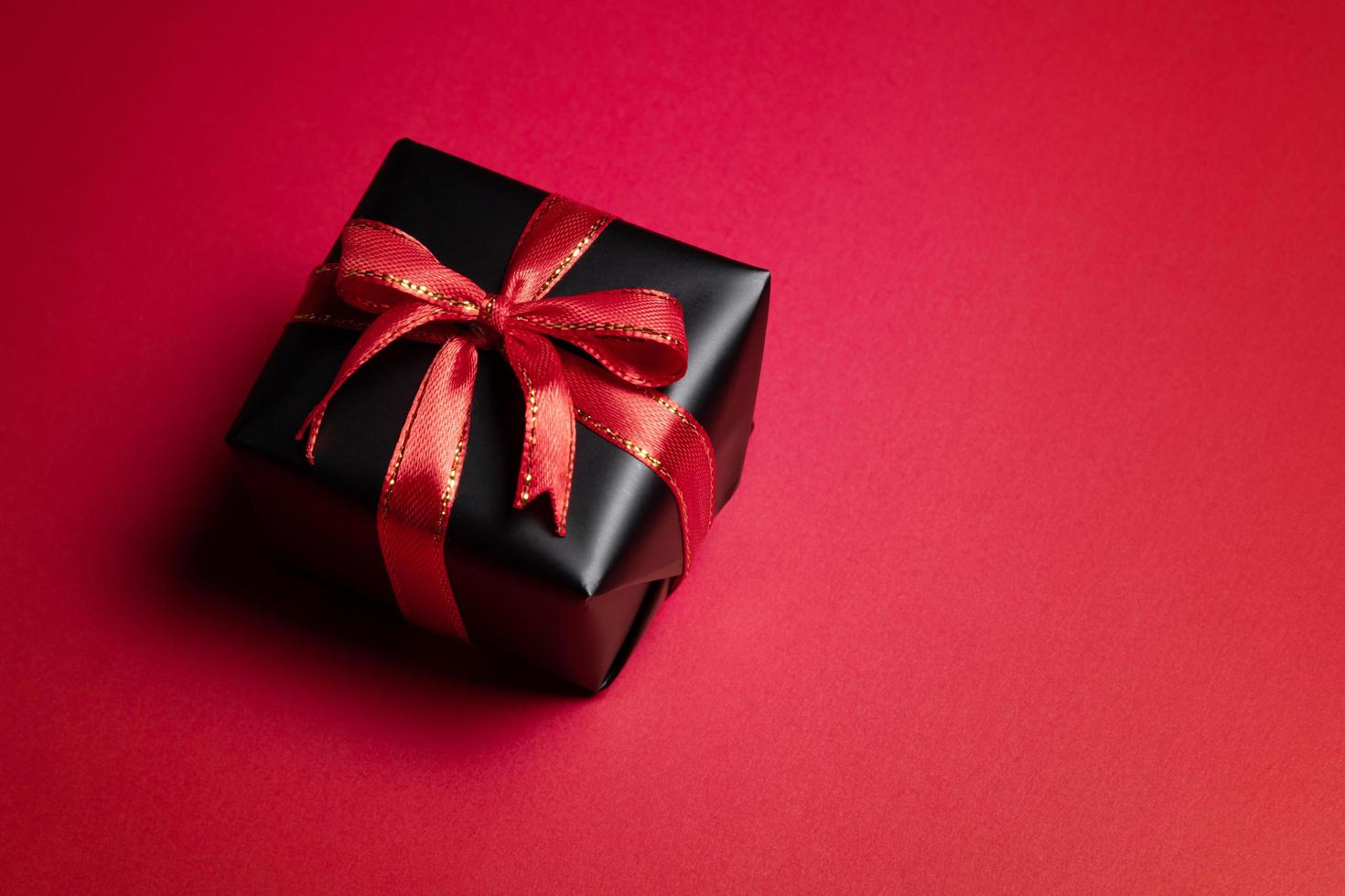 Top view of black gift box with red and black ribbons isolated on red background. photo