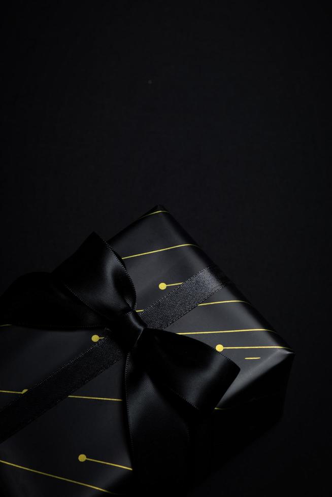 Top view of black gift box with black ribbons isolated on black background. photo