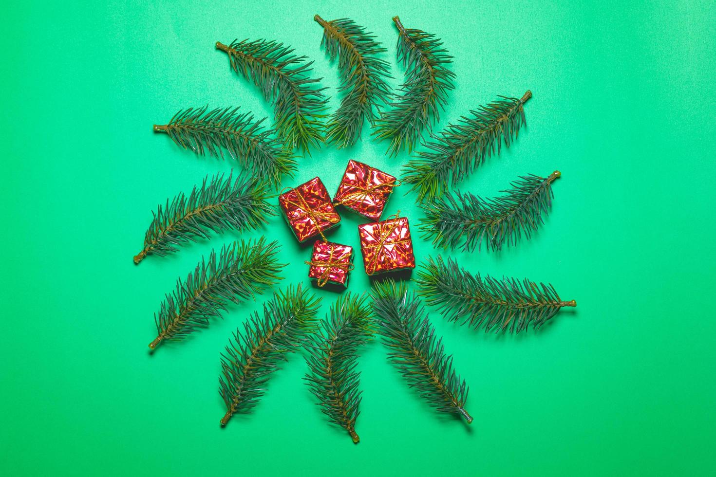 Top view of Christmas gift box red balls with spruce branches and bell on green background. photo