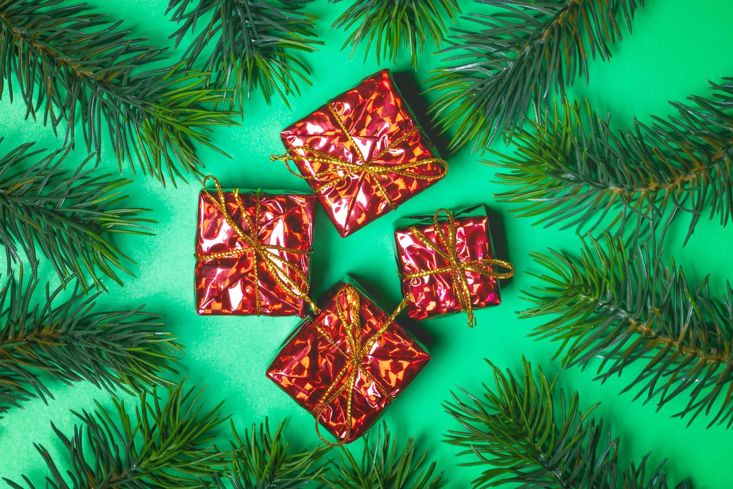 Top view of Christmas gift box red balls with spruce branches and bell on green background. photo