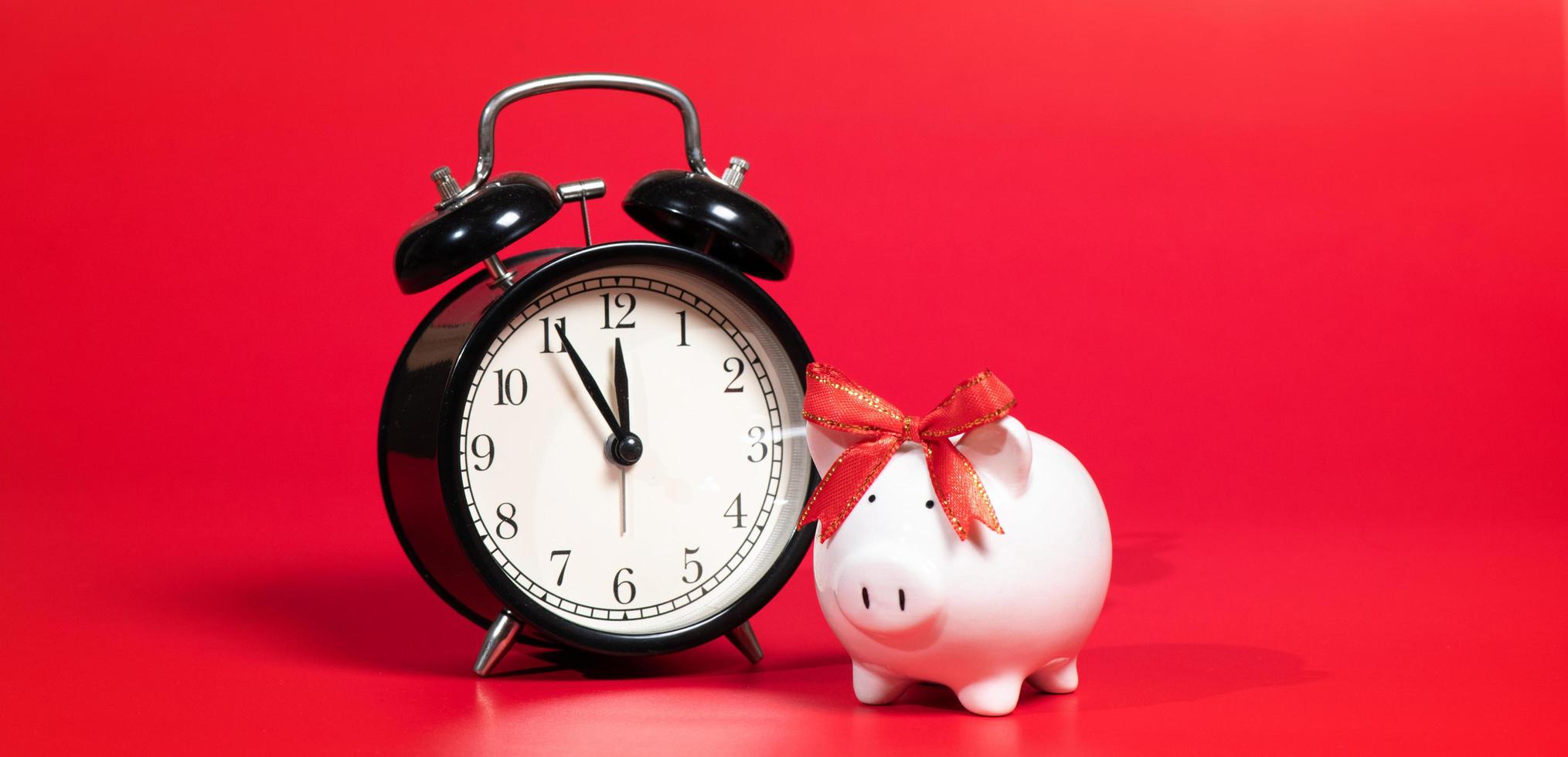 Composition with piggy bank and clock isolated on red background. photo