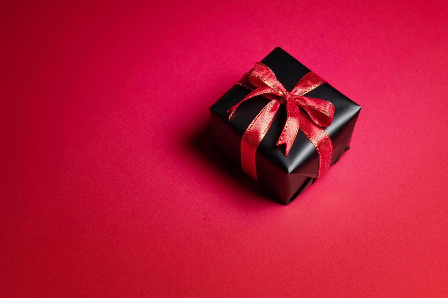 Top view of black gift box with red and black ribbons isolated on red background. photo