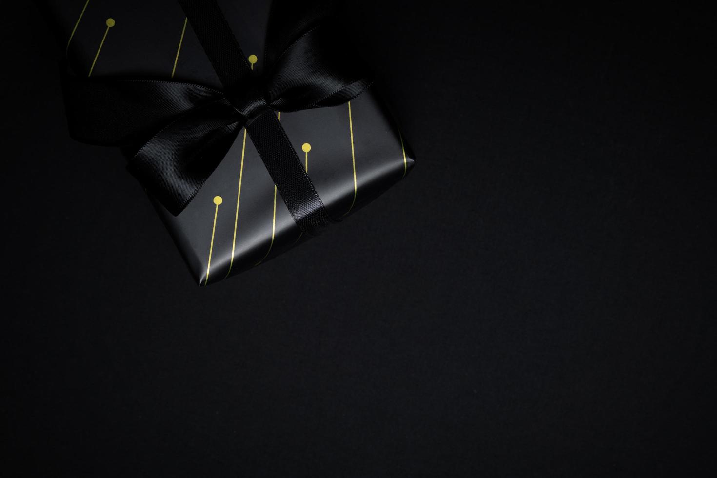 Top view of black gift box with black ribbons isolated on black background. photo