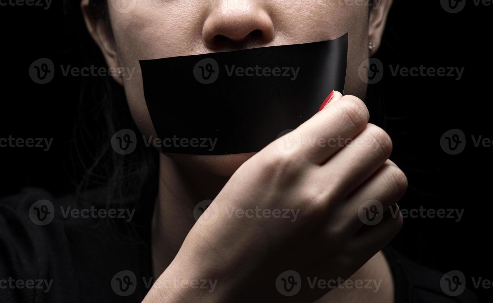 The girl's face is sealed her mouth with black paper Premium Photo