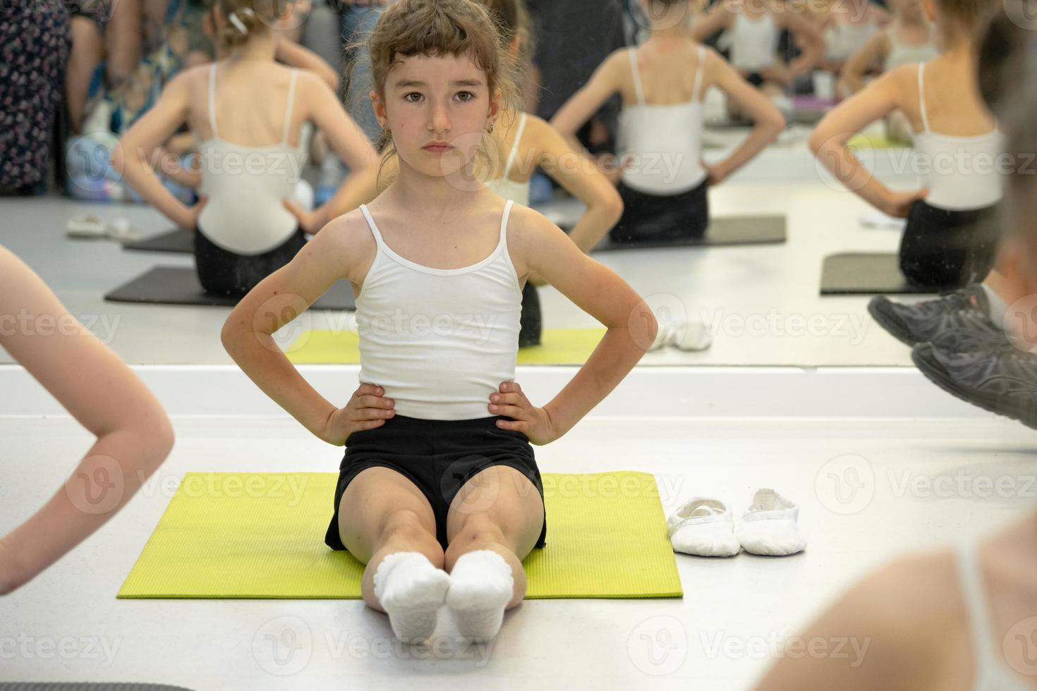 Child trains in gym on the mat, does stretching exercises and abs, gymnastics and general physical sport training. Working on yourself and your body since childhood, overcoming yourself photo