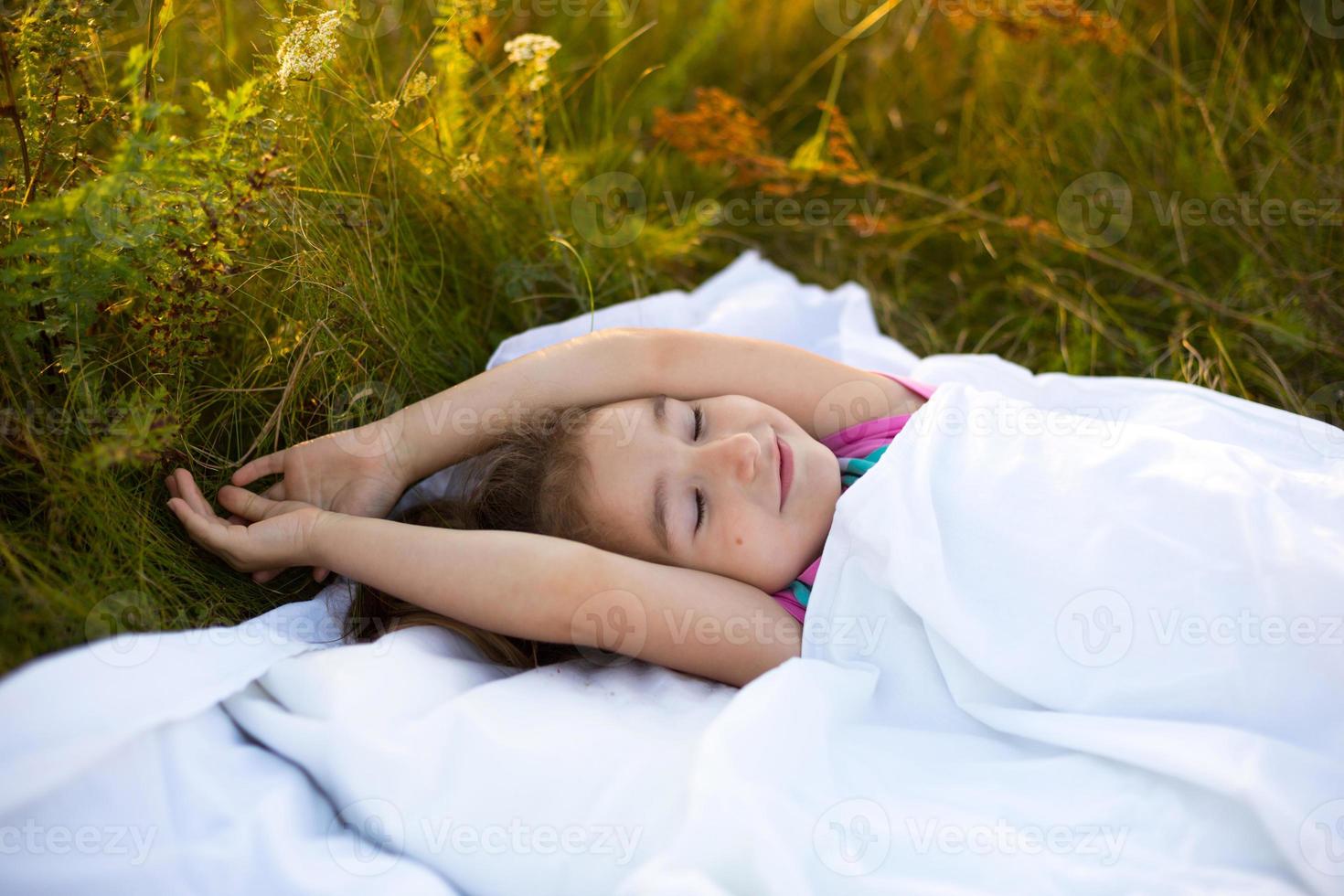 Girl sleeps on bed in grass, Sweet stretches and yawns sleepily, good morning in fresh air. Eco-friendly, healthy sleep, Protection from mosquitoes, clean nature, ecology, children's health photo