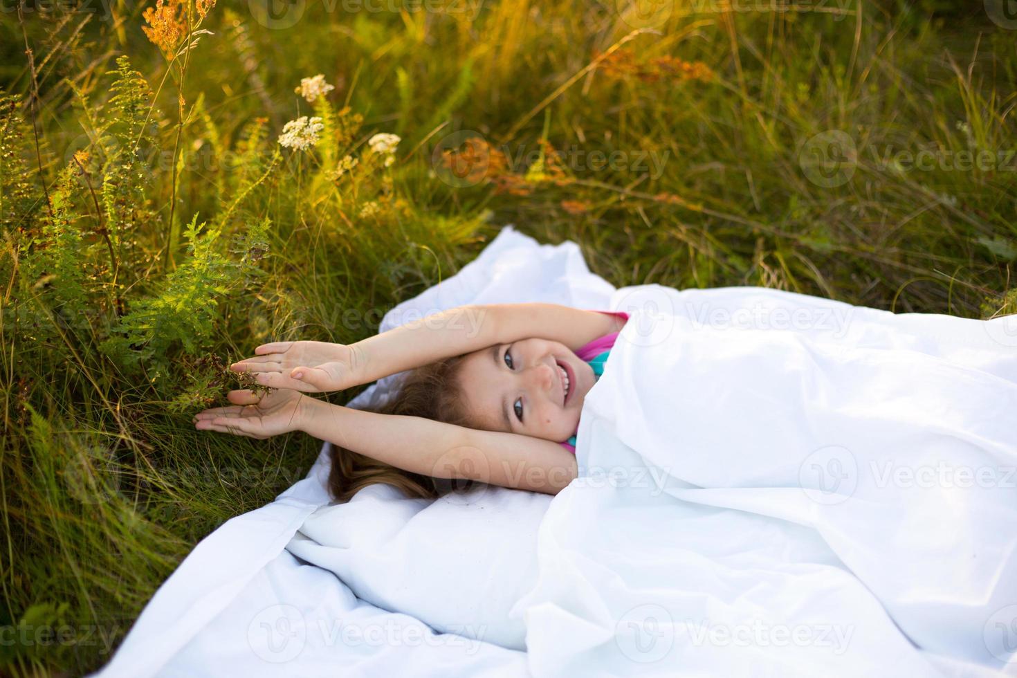 Girl sleeps on bed in grass, Sweet stretches and yawns sleepily, good morning in fresh air. Eco-friendly, healthy sleep, Protection from mosquitoes, clean nature, ecology, children's health photo