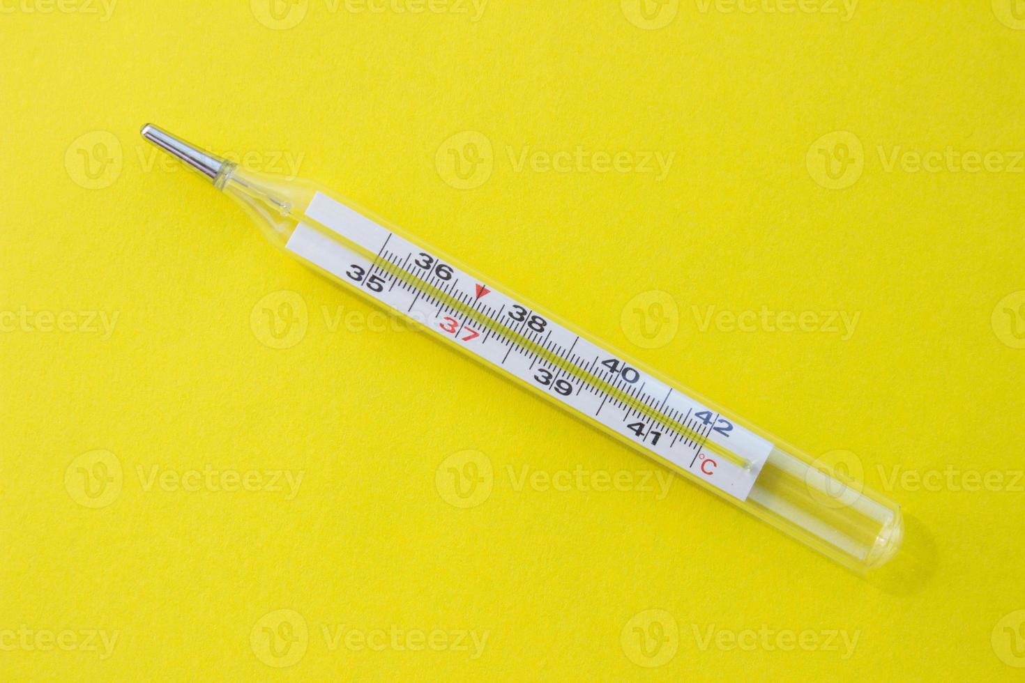 Mercury thermometer on a yellow background. Single object photo