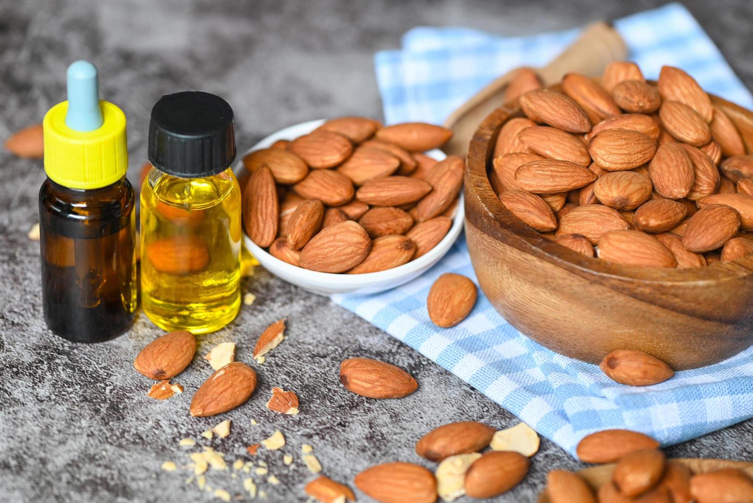 aceite de almendras y nueces de almendras en el bol, delicioso aceite de almendras dulces en botella de vidrio, nueces de almendras tostadas para alimentos saludables y aceites vegetales orgánicos para cocinar o spa foto