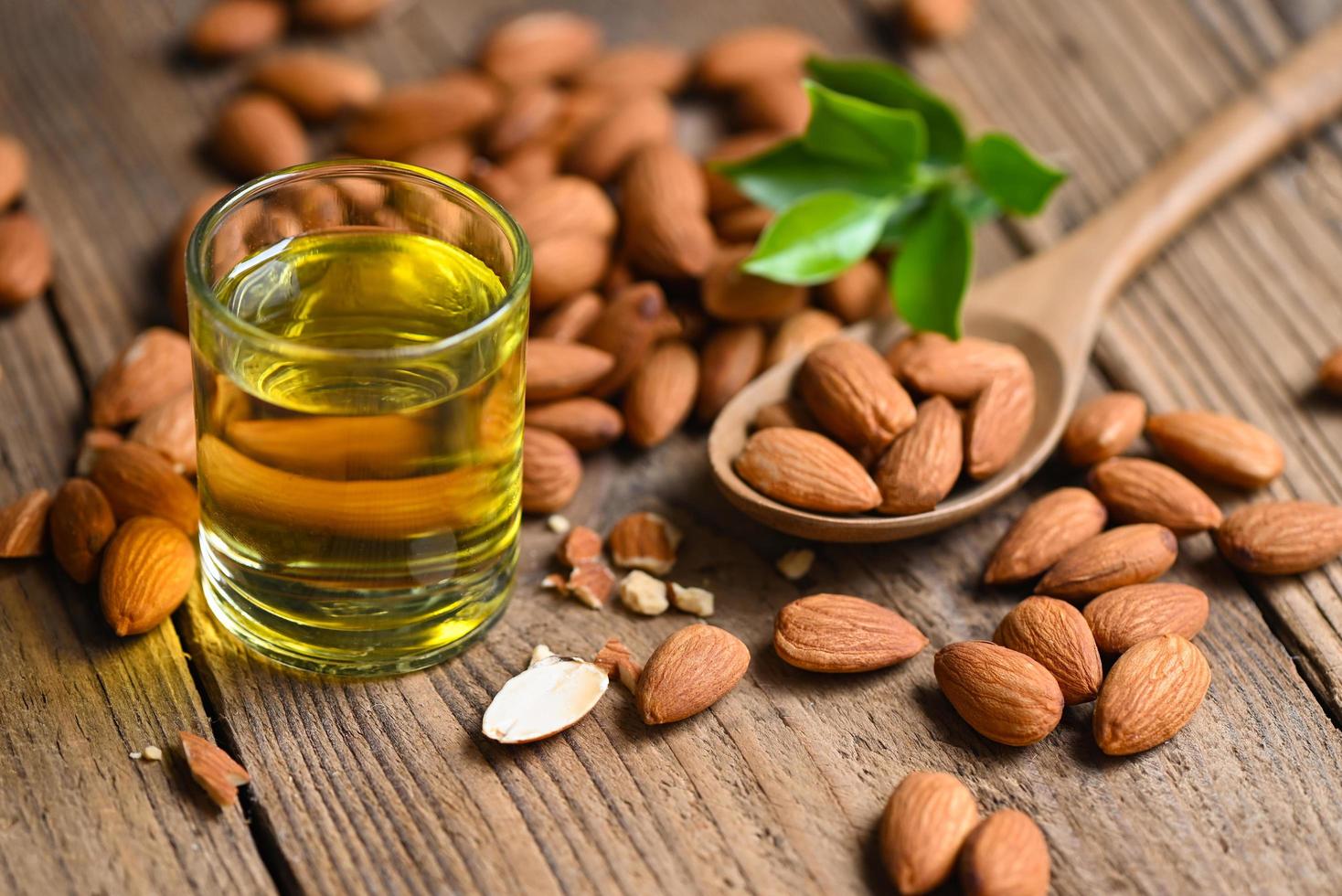 Almond oil and Almonds nuts on wooden, Delicious sweet almonds oil in glass, roasted almond nut for healthy food and snack organic vegetable oils for cooking or spa photo