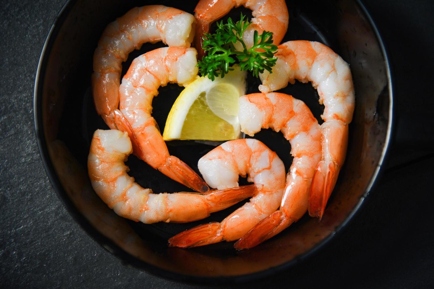 Shrimps prawns seafood plate cooked on pan with herbs and spices lemon and curly parsley photo