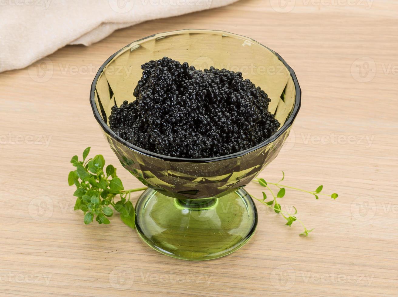 Black caviar in a bowl on wooden background photo