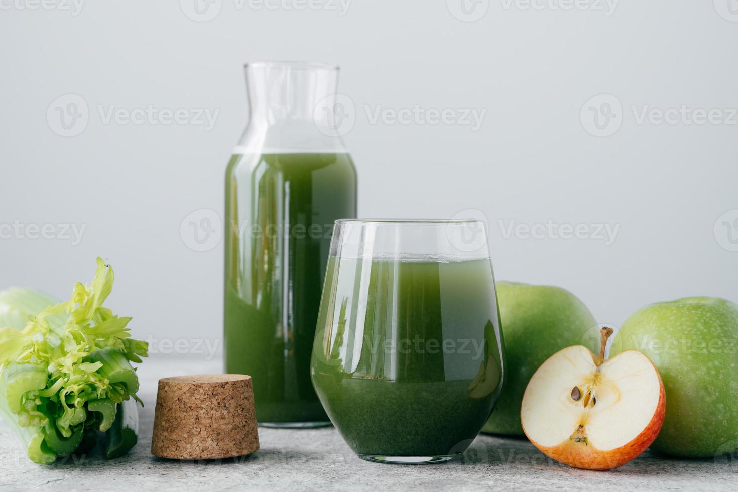 Green healthy celery and apple juice in glassware. Vegetable drink. Fresh smoothie isolated over white background. Organic beverage photo