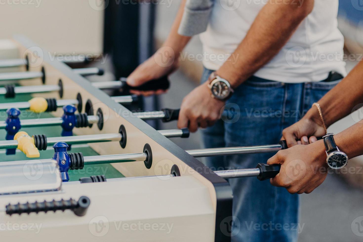 Friends play football soccer game, being gamblers. Men play in kicker together as team. Football match. Competition and entertainment concept photo