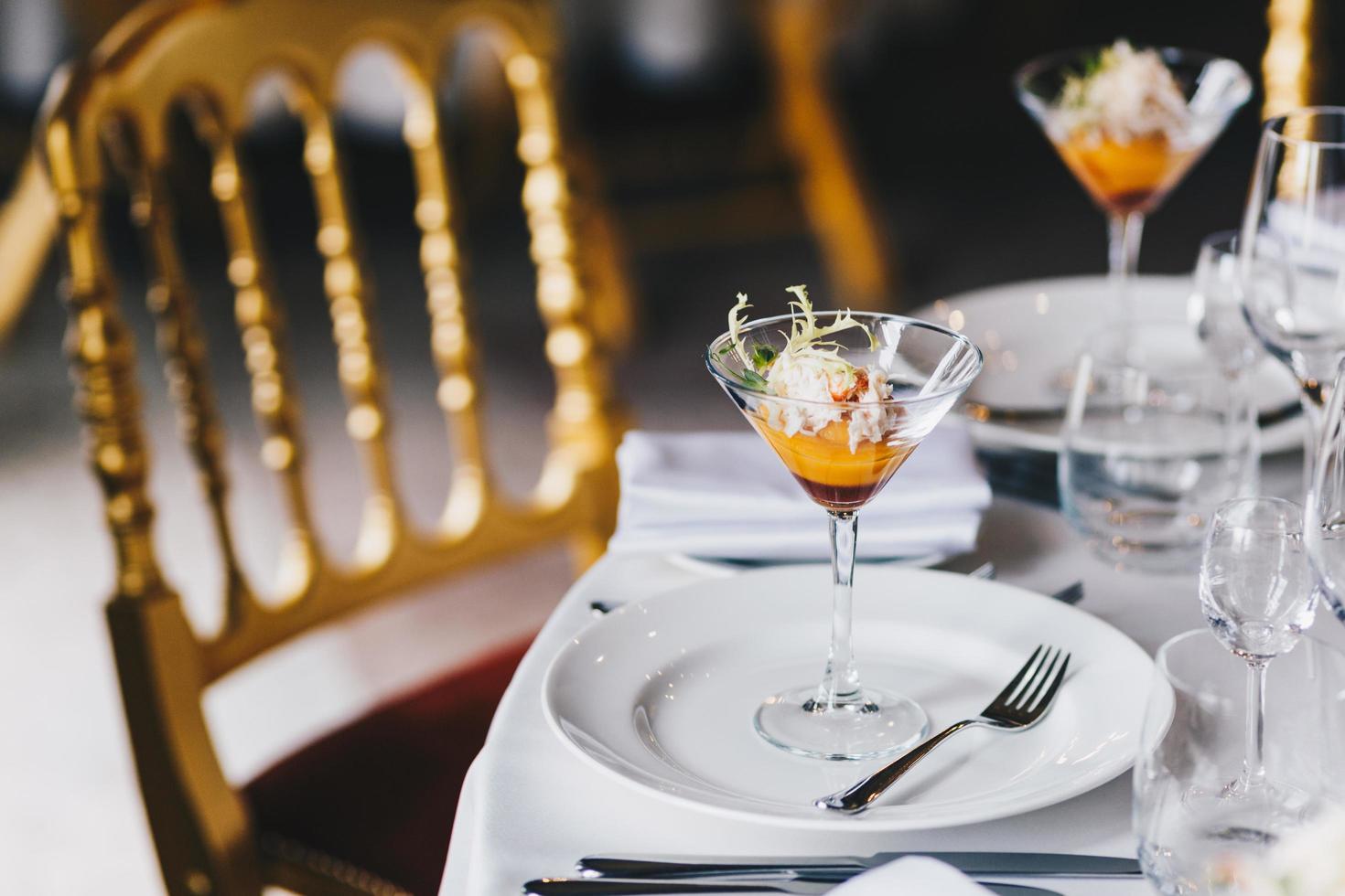 Table setting with beautifully decoration, tasty cocktail and white cutlery for festive event. Luxury resturant with no people. Wedding reception. Dinner set up. Cozy atmopshere. photo