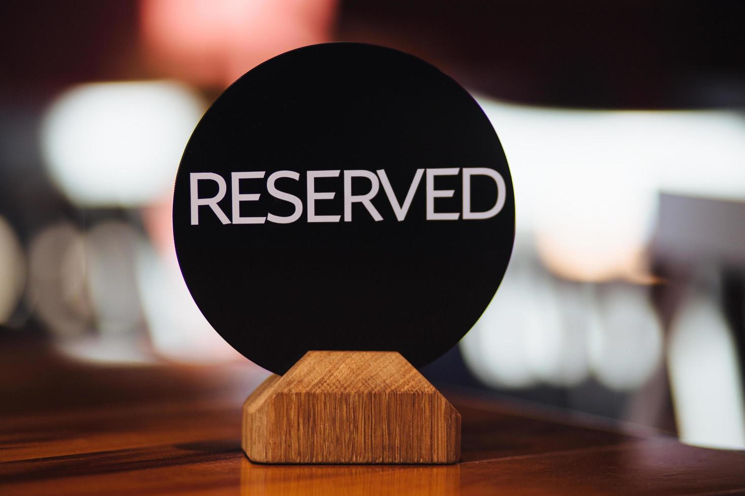 Booked table in restaurant with sign reserved against blurred backgrounnd. Restaurant scene concept. Reserved desk for special moment. Table booked for lunch. photo