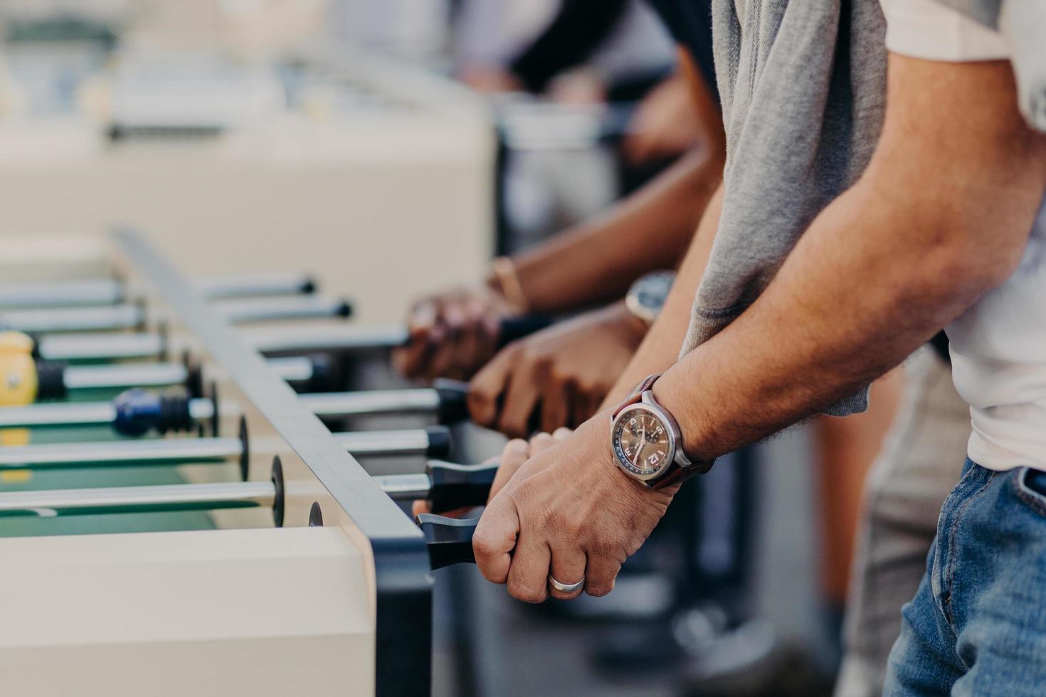 Table football kicker. Best friends enjoy togetherness, recreat in entertainment place, play table soccer together, have free time. People and rest concept photo