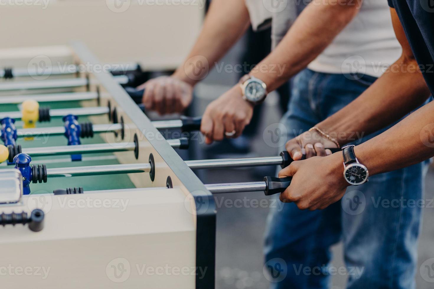 Cropped view of males hands play table football, enjoy recreation or leisure time during holidays, spend free time in bar. Competition concept photo