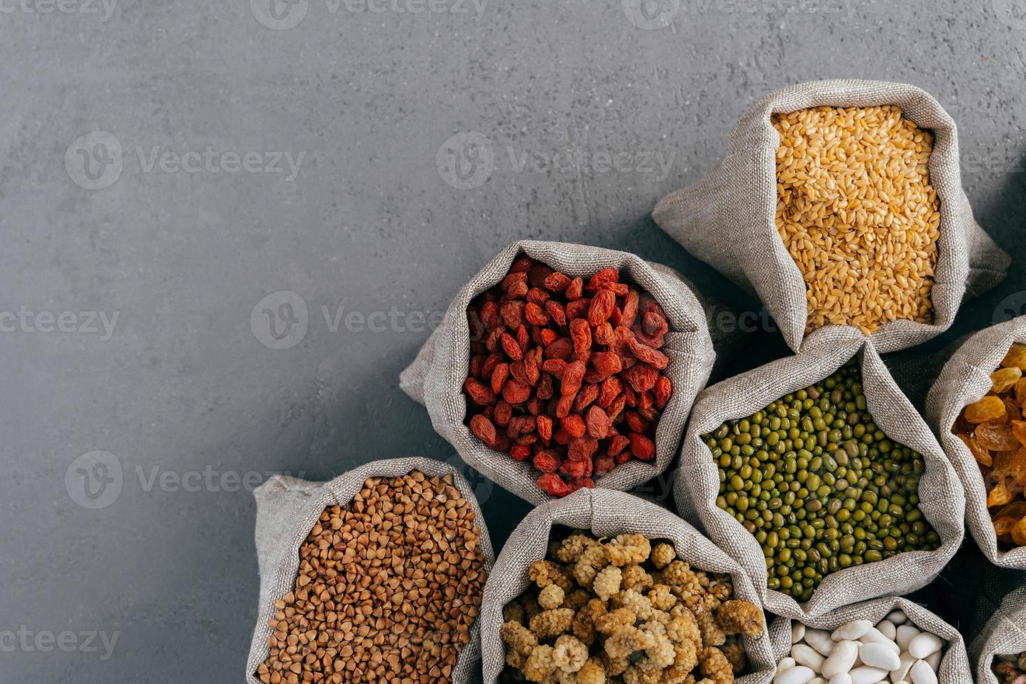 sacos con goji rojo, trigo sarraceno, guisante de Jerusalén, morera, frijol aislado sobre fondo gris con espacio de copia para su información foto